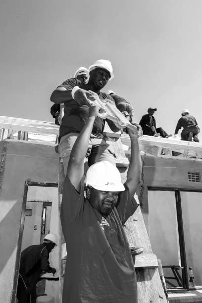 Factory-trained roofing installation team working on long-span aluminium sheets